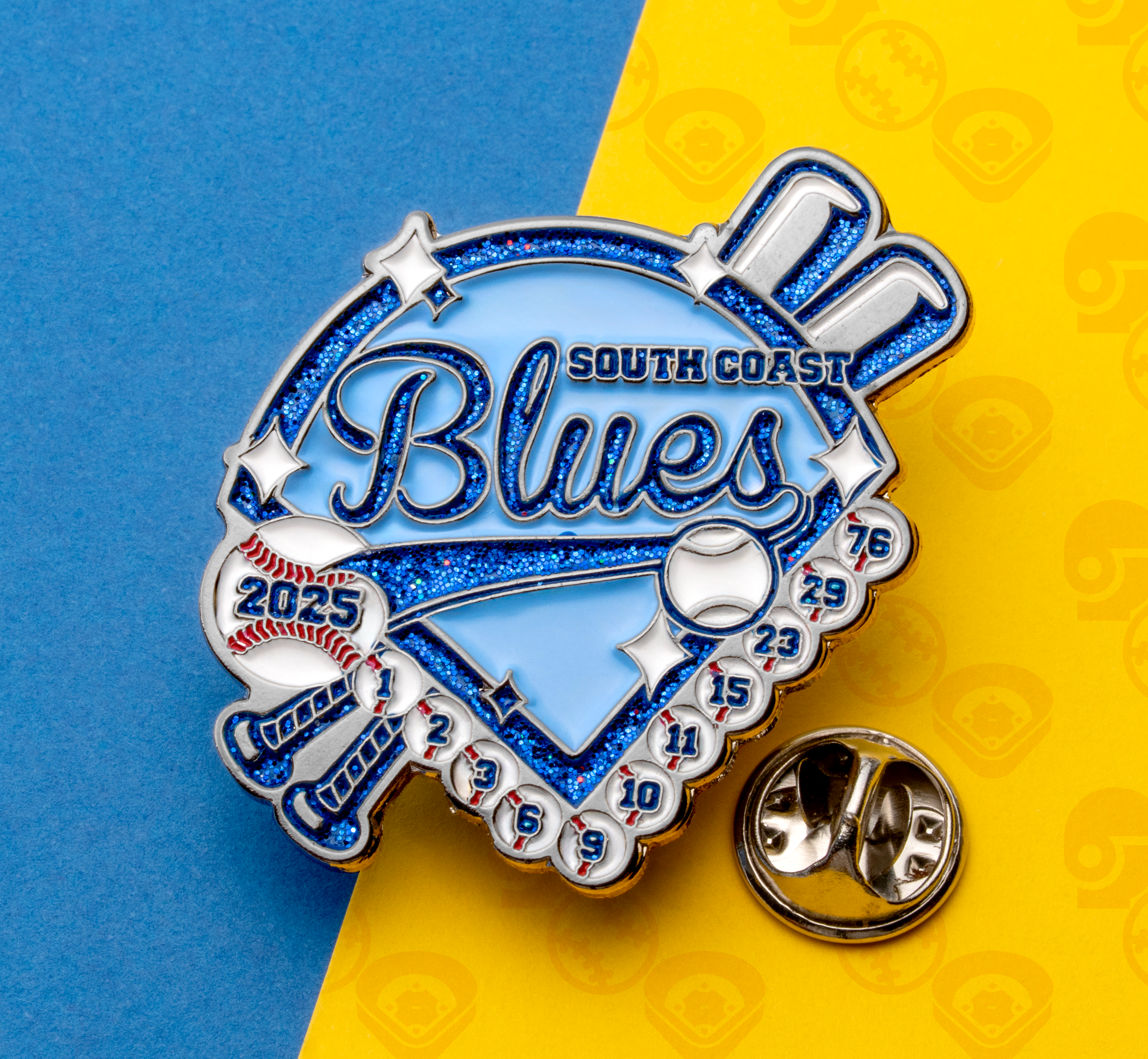 Custom baseball trading pin for South Coast Blues featuring a blue glitter diamond, crossed bats, and small baseballs with jersey numbers.