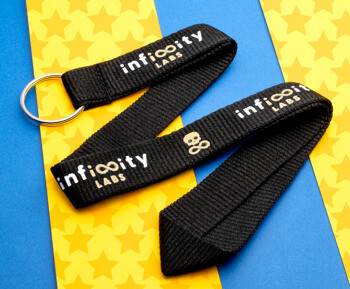 Black woven lanyard with Infinity Labs logo and skull icon on a yellow and blue background.