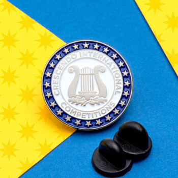 Circular lapel pin for Crescendo International Competitions featuring a silver lyre icon on a white background with a blue star border.