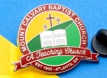 Enamel lapel pin for Mount Calvary Baptist Church featuring three crosses, a Holy Bible icon, and a red banner on a blue and yellow background.