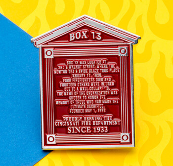 Red and silver architectural house-shaped lapel pin featuring historical text about Box 13 and the Cincinnati Fire Department.