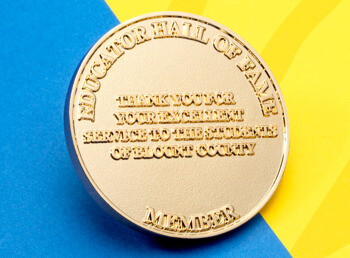 Gold round challenge coin featuring raised text for Educator Hall of Fame Member Blount County.