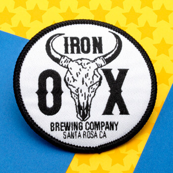 Circular embroidered patch for Iron Ox Brewing Company featuring an ox skull logo and black border on a blue and yellow background.